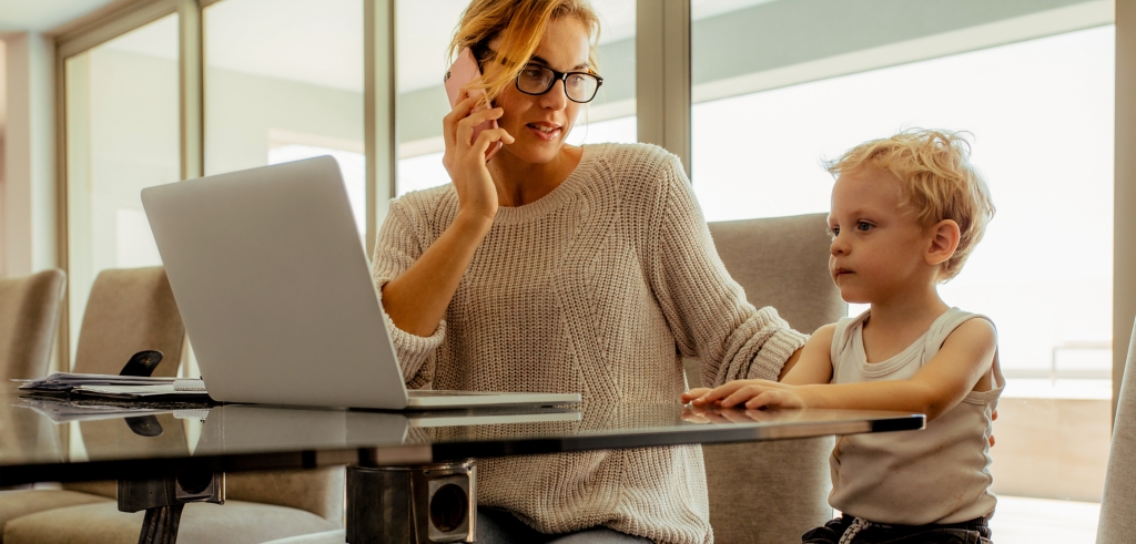 Mother working with child sitting next to her
